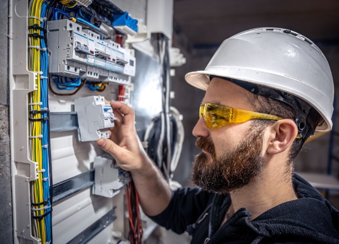 male-electrician-works-switchboard-with-electrical-connecting-cable